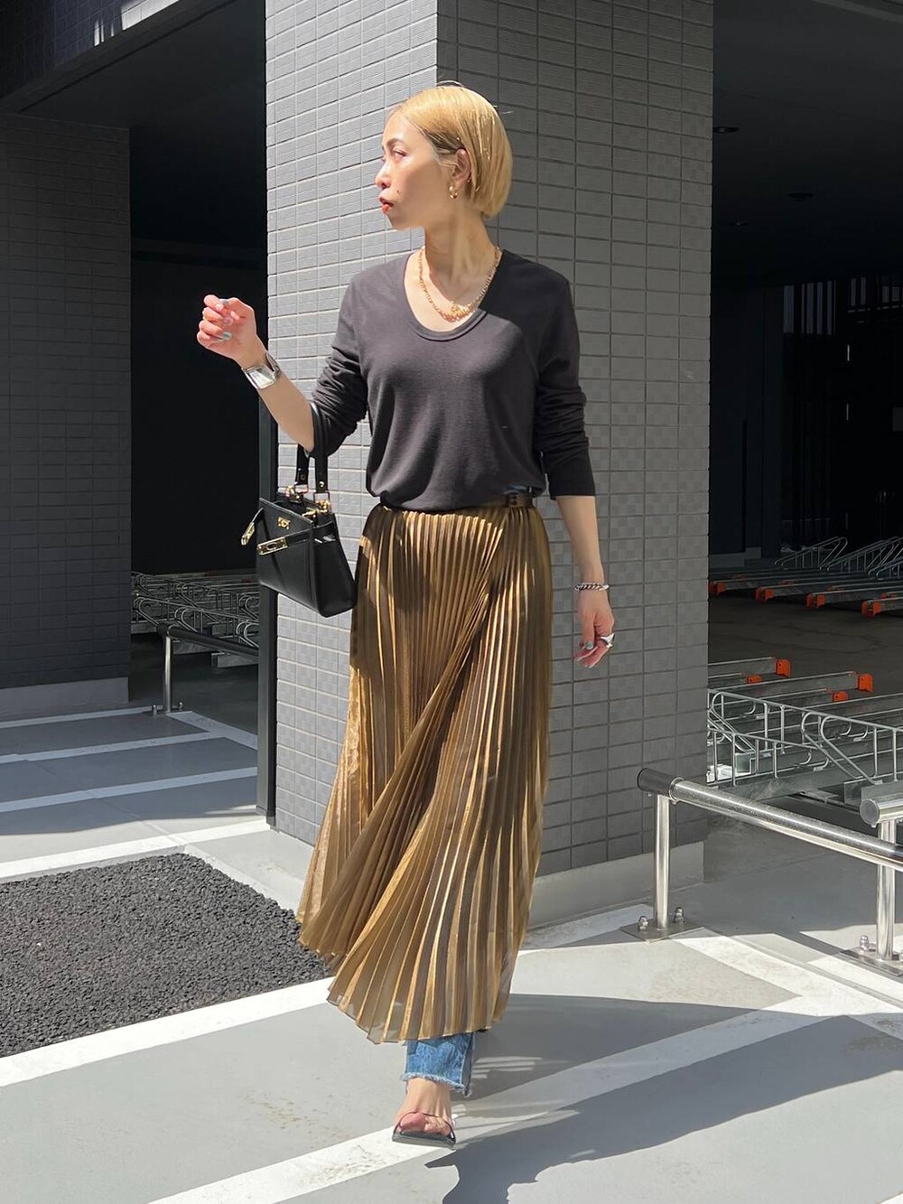 ゴールド系のスカートを着用したレディースの春コーディネートの2枚目の写真