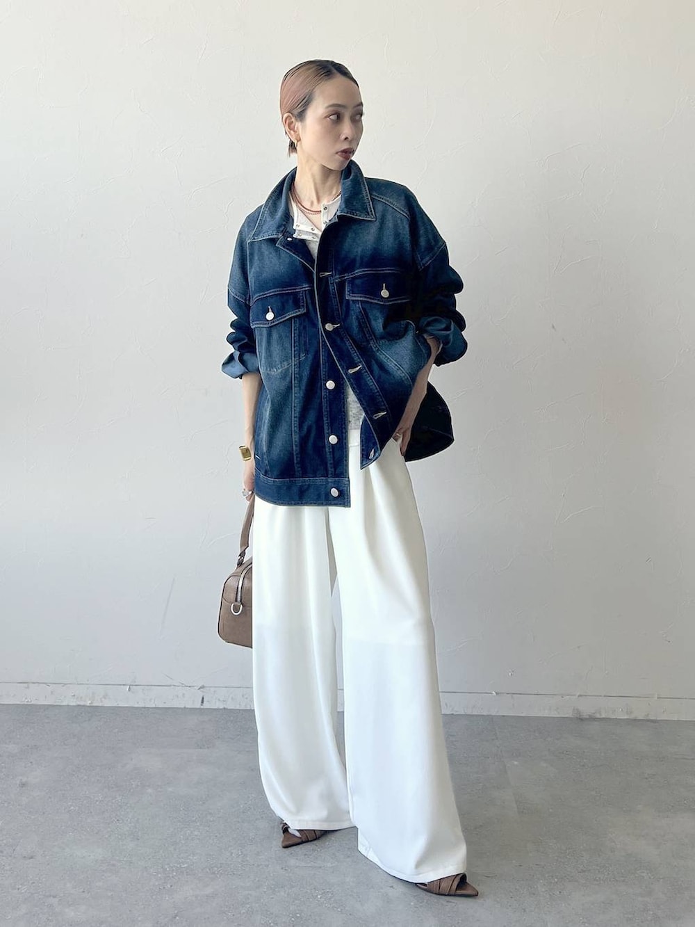 ブラウン系のボストンバッグ、ブルー系のブルゾン、グレー系のTシャツ/カットソーを着用したレディースの春コーディネートの4枚目の写真