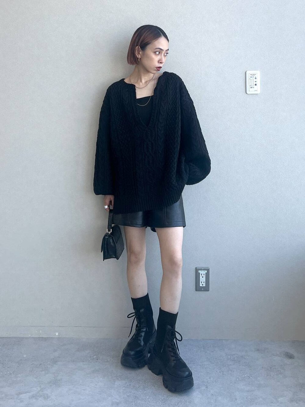 ブラック系のブーツ、ブラック系のハンドバッグ、ブラック系のニット/セーターを着用したレディースの秋コーディネートの3枚目の写真