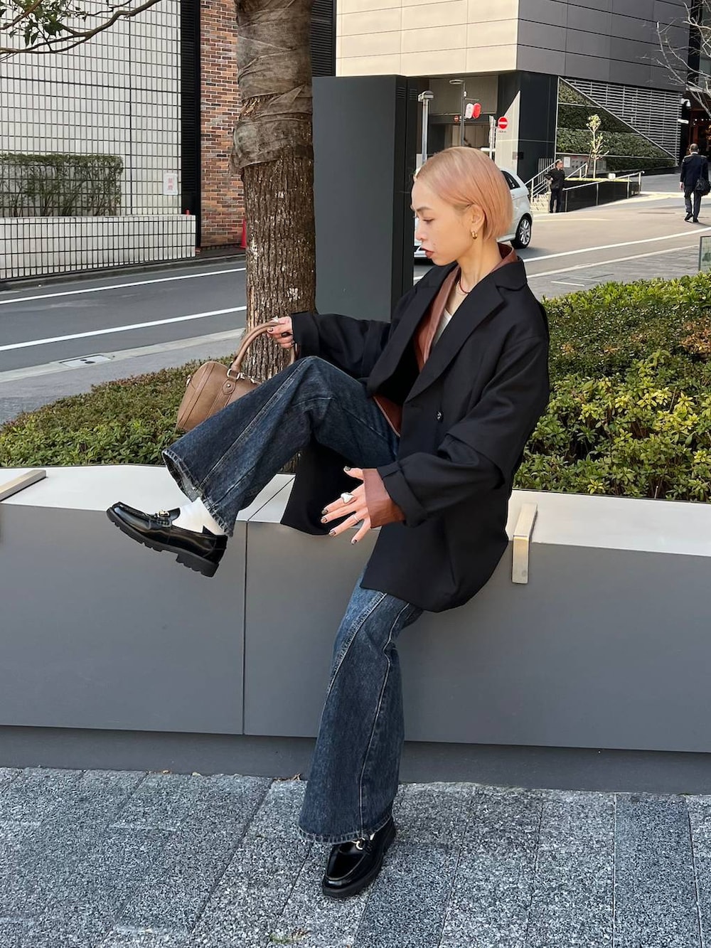 ブルー系のデニムパンツ、ブラウン系のボストンバッグ、ブラック系のテーラードジャケットを着用したレディースの春コーディネートの4枚目の写真