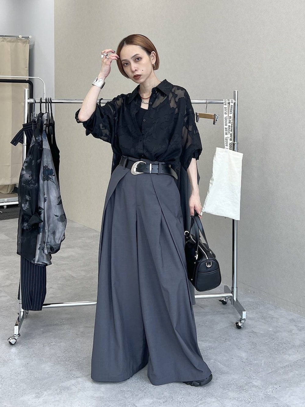 ブラック系のショルダーバッグ、ブラック系のシャツ/ブラウス、グレー系のスラックスを着用したレディースの夏コーディネートの6枚目の写真