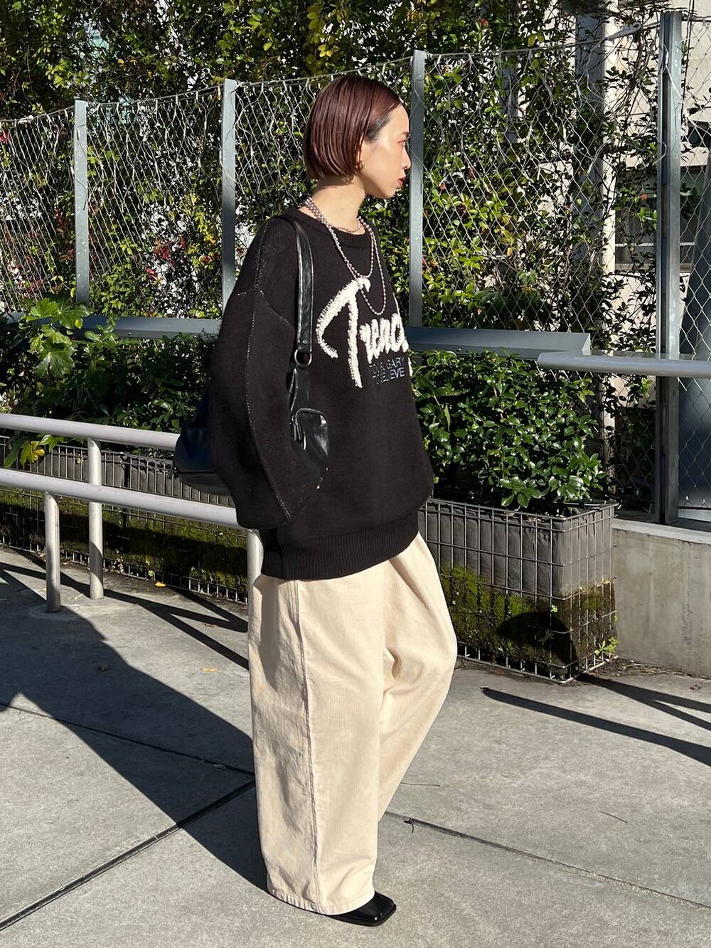 ブラック系のショルダーバッグ、ブラック系のブーツ、ブラック系のニット/セーターを着用したレディースの冬コーディネートの3枚目の写真