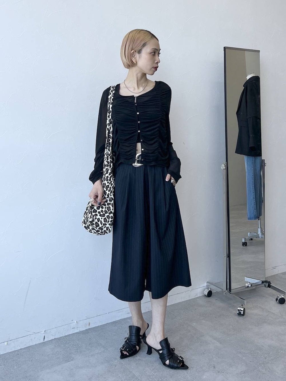 ブラック系のTシャツ/カットソー、ブルー系のスラックス、ブラック系のサンダルを着用したレディースの春コーディネートの6枚目の写真