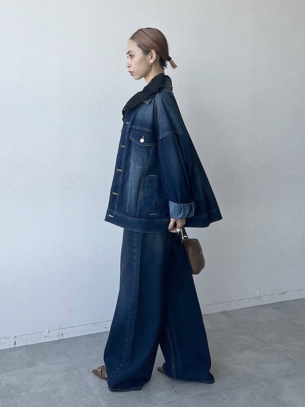 ブルー系のスラックス、ブラウン系のボストンバッグ、ブルー系のブルゾンを着用したレディースの春コーディネートの3枚目の写真