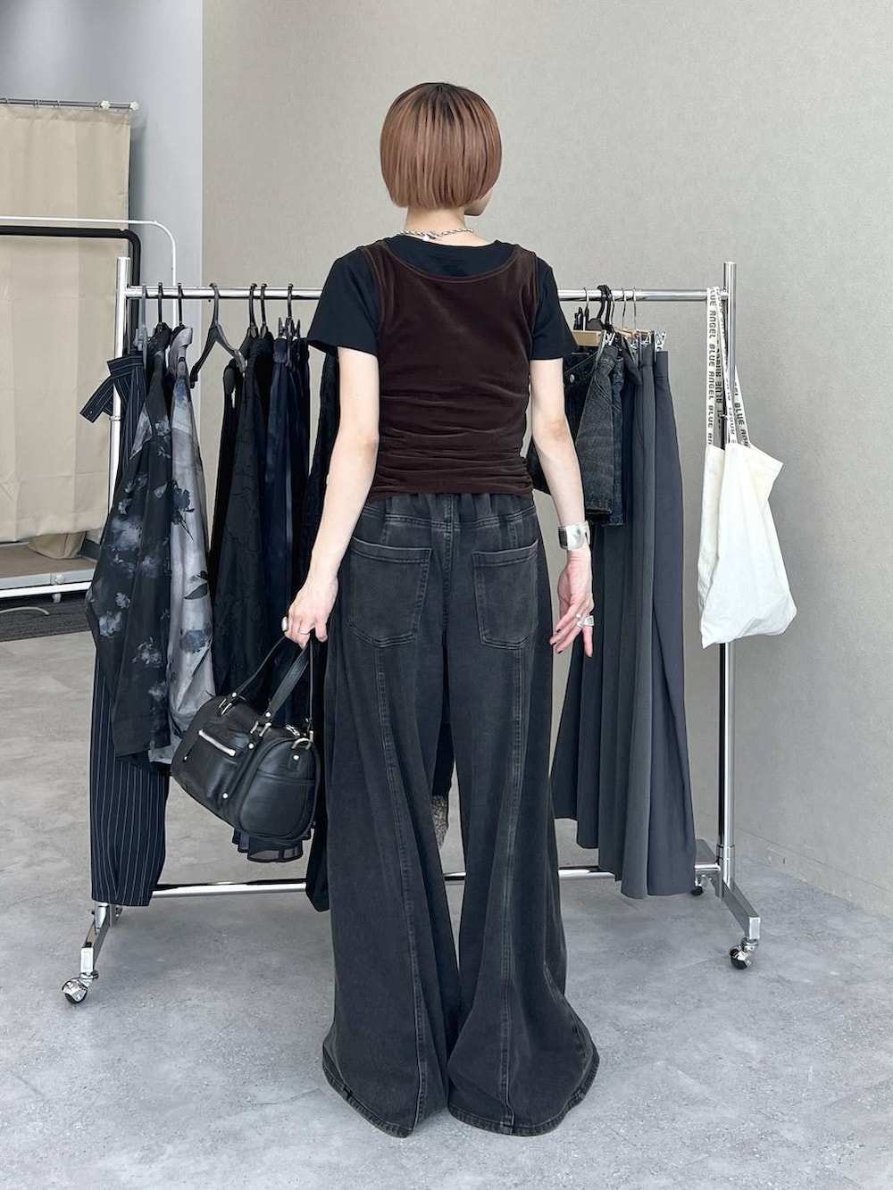 ブラック系のデニムパンツ、ブラック系のショルダーバッグ、ブラウン系のタンクトップを着用したレディースの夏コーディネートの4枚目の写真