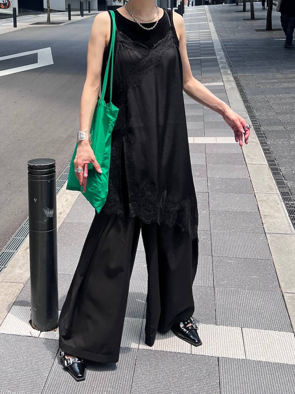 ブラック系のチュニック、ブラック系のスラックス、ブラック系のタンクトップを着用したレディースの夏コーディネートの10枚目の写真