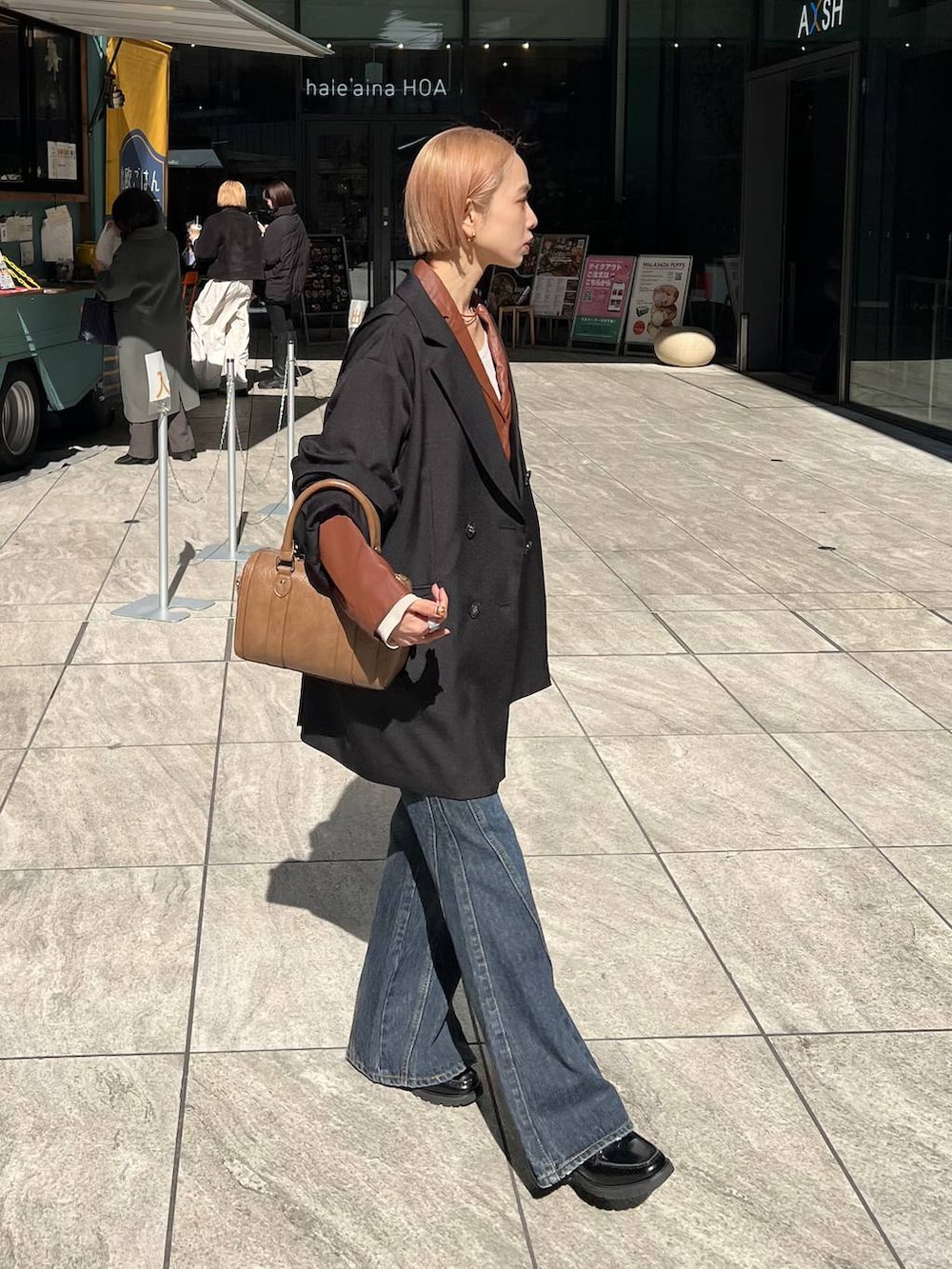 ブルー系のデニムパンツ、ブラウン系のボストンバッグ、ブラック系のテーラードジャケットを着用したレディースの春コーディネートの5枚目の写真