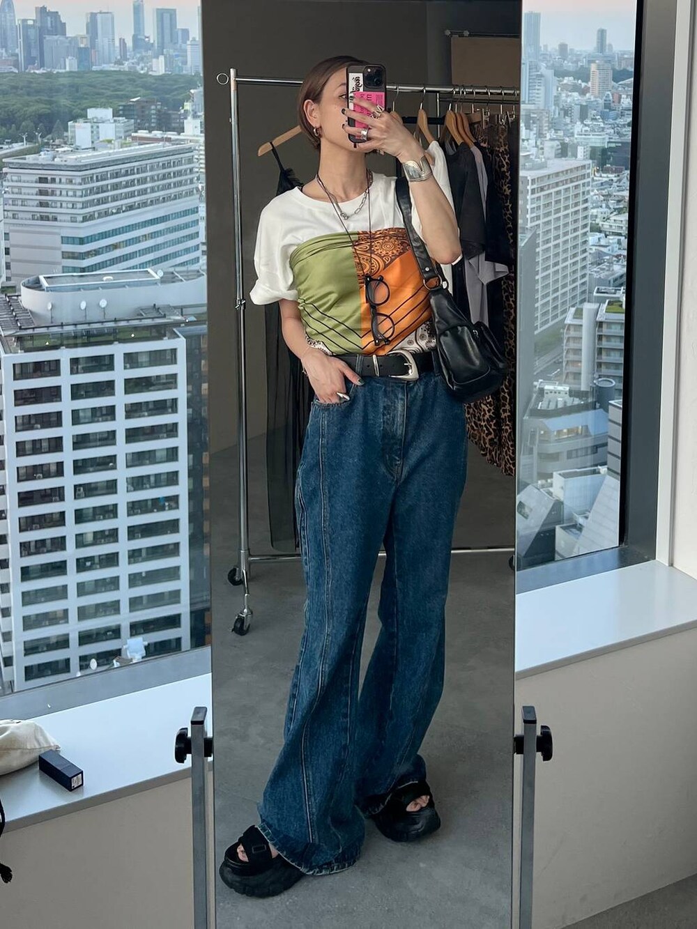 ブラック系のショルダーバッグ、ブラック系のサンダル、ブルー系のデニムパンツを着用したレディースの夏コーディネートの2枚目の写真