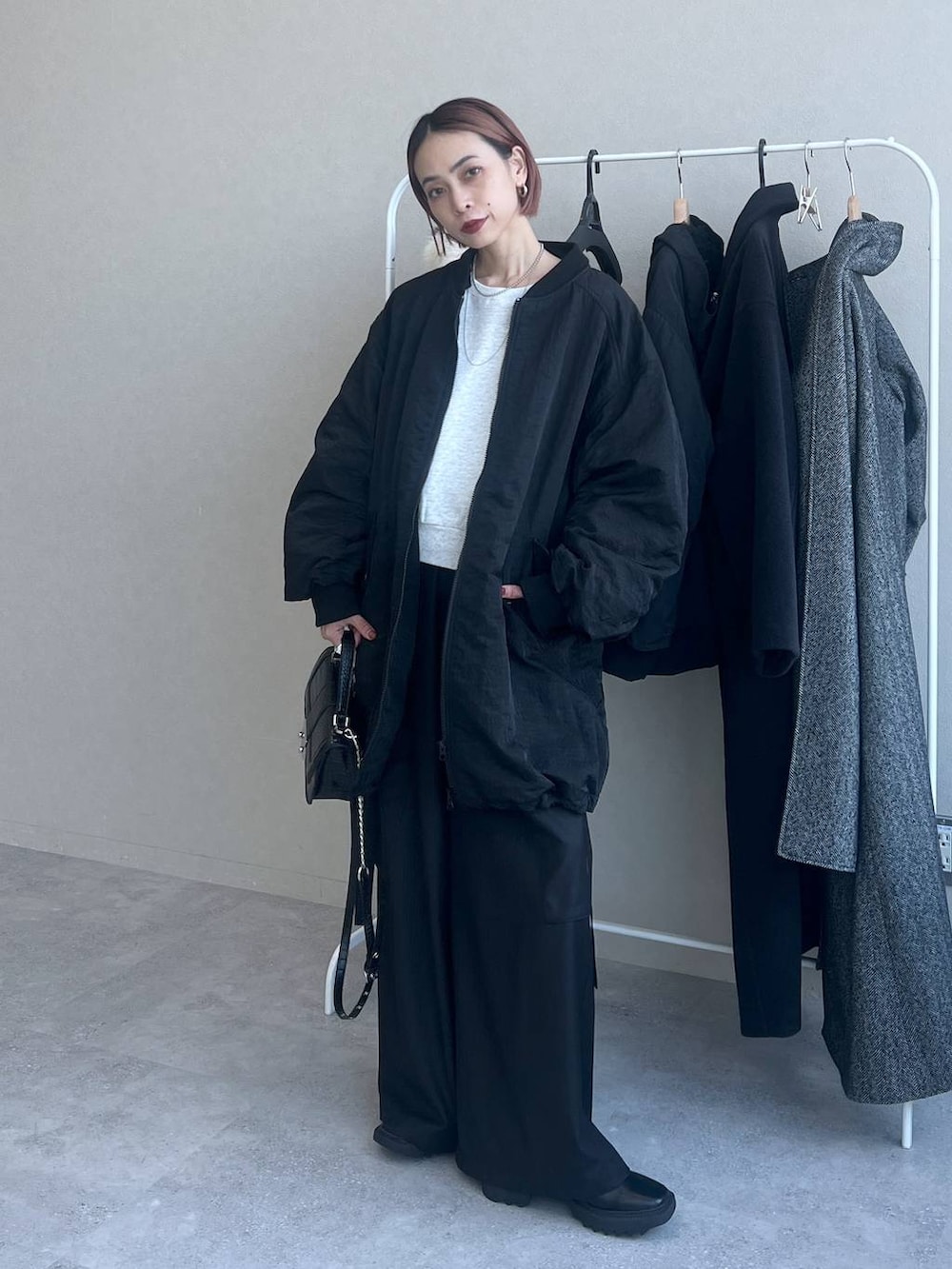 ブラック系のハンドバッグ、ブラック系のスラックス、ブラック系のブルゾンを着用したレディースの秋コーディネートの2枚目の写真