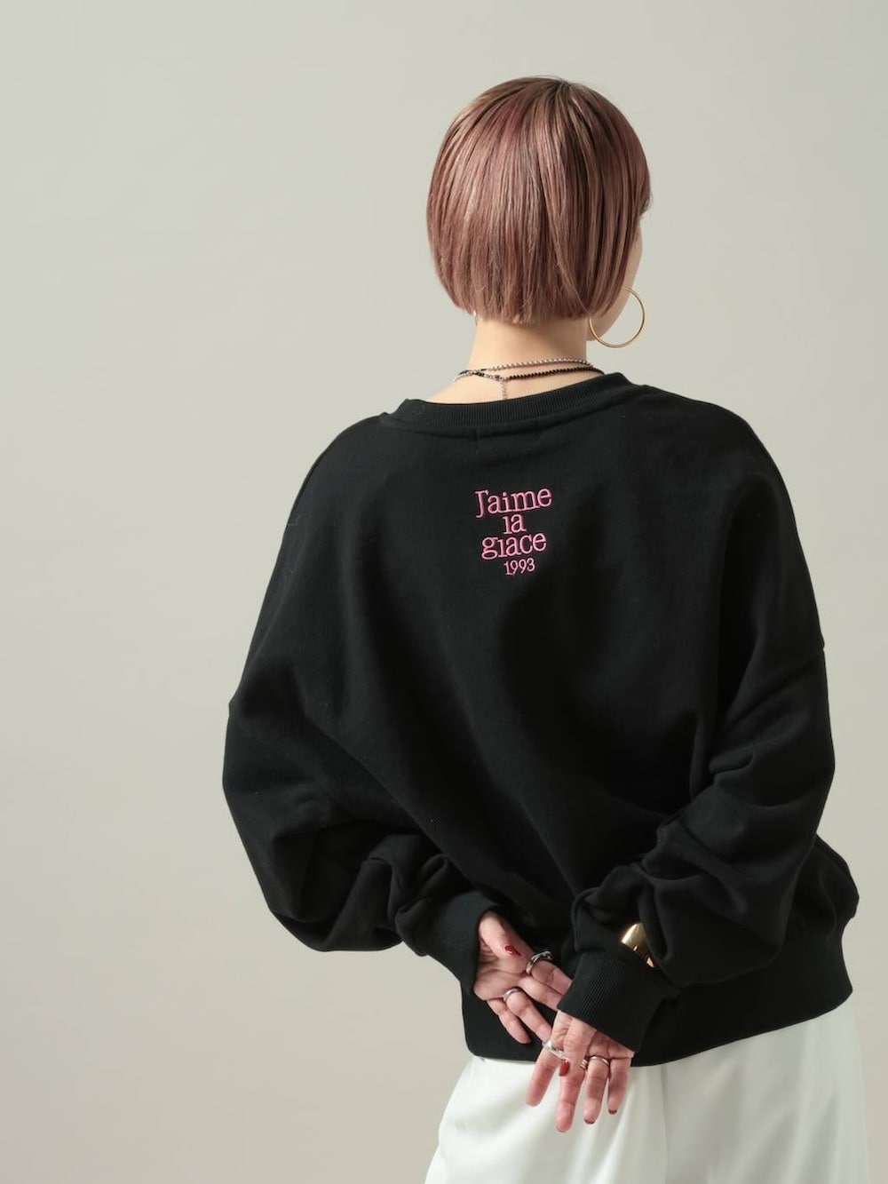 ブラック系のスウェット、ホワイト系のスラックスを着用したレディースの冬コーディネートの2枚目の写真