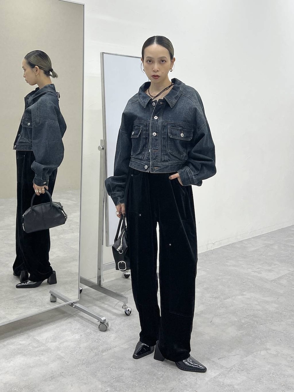 ブラック系のショルダーバッグ、ブルー系のデニムジャケット、ブラック系のその他パンツを着用したレディースの秋コーディネートの4枚目の写真