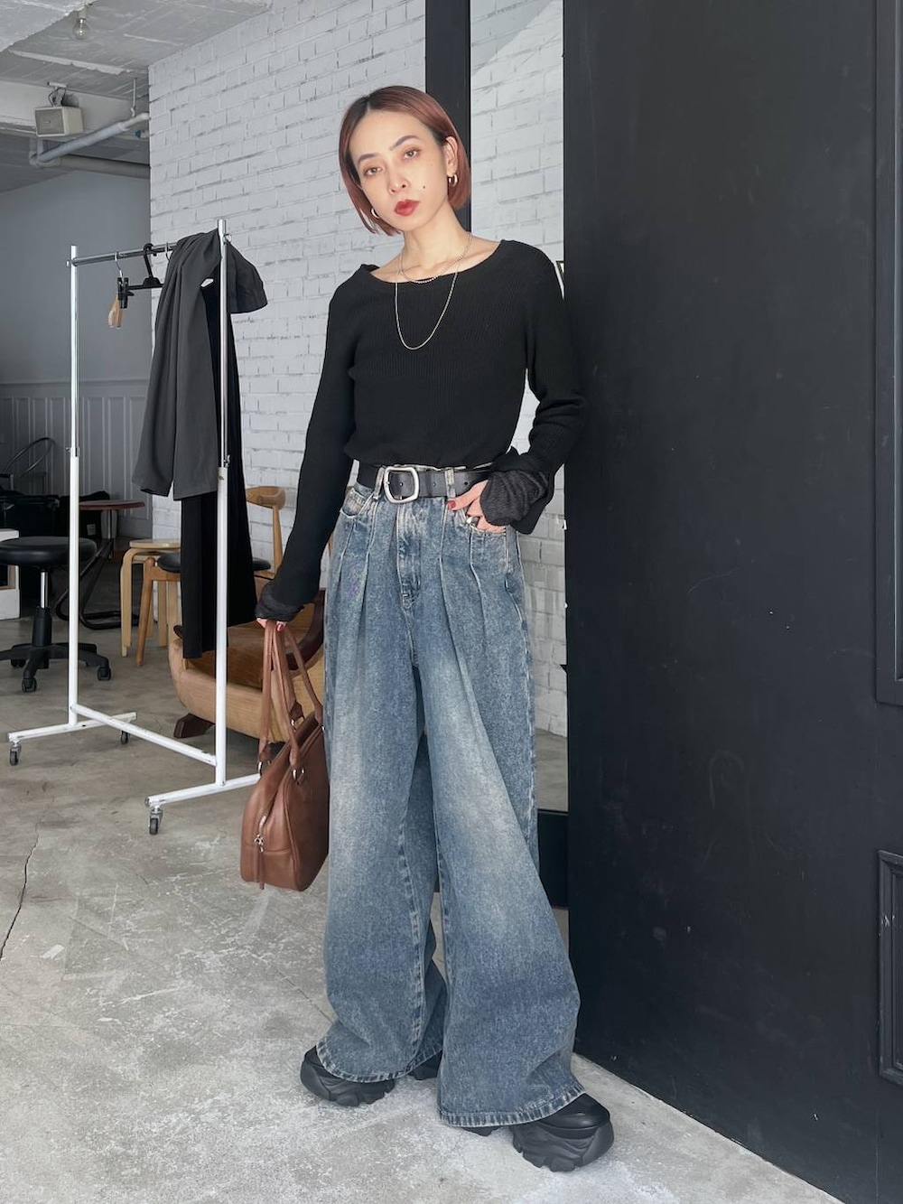 ブラック系のスニーカー、ブルー系のデニムパンツ、イエロー系のボストンバッグを着用したレディースの秋コーディネートの4枚目の写真