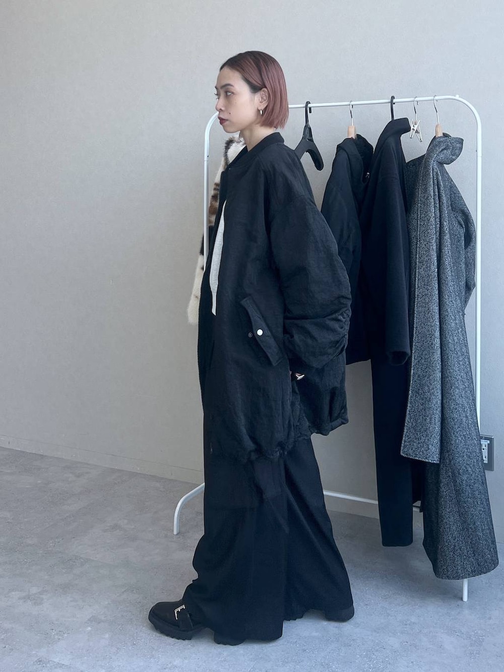 ブラック系のハンドバッグ、ブラック系のスラックス、ブラック系のブルゾンを着用したレディースの秋コーディネートの3枚目の写真