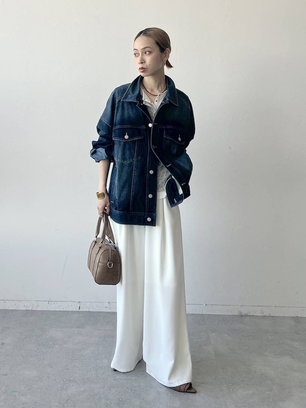 ブラウン系のボストンバッグ、ブルー系のブルゾン、グレー系のTシャツ/カットソーを着用したレディースの春コーディネートの5枚目の写真