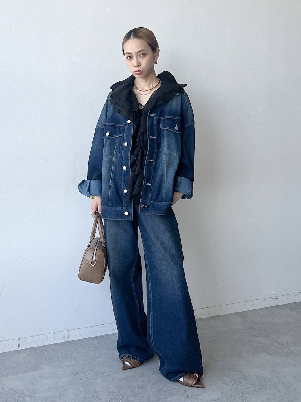 ブルー系のスラックス、ブラウン系のボストンバッグ、ブルー系のブルゾンを着用したレディースの春コーディネートの4枚目の写真