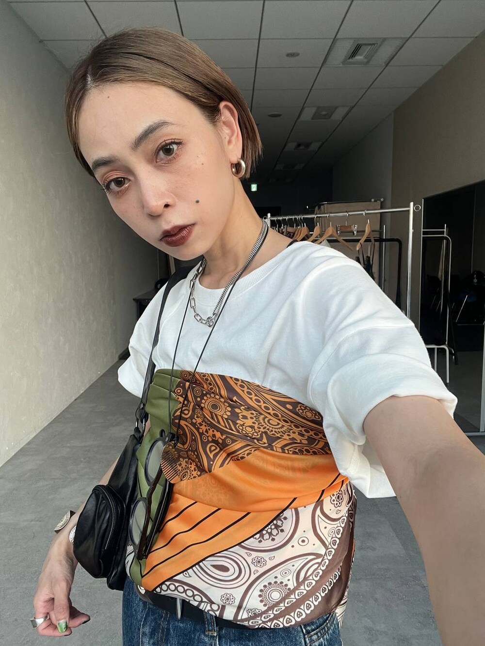 ブラック系のショルダーバッグ、ブラック系のサンダル、ブルー系のデニムパンツを着用したレディースの夏コーディネートの5枚目の写真