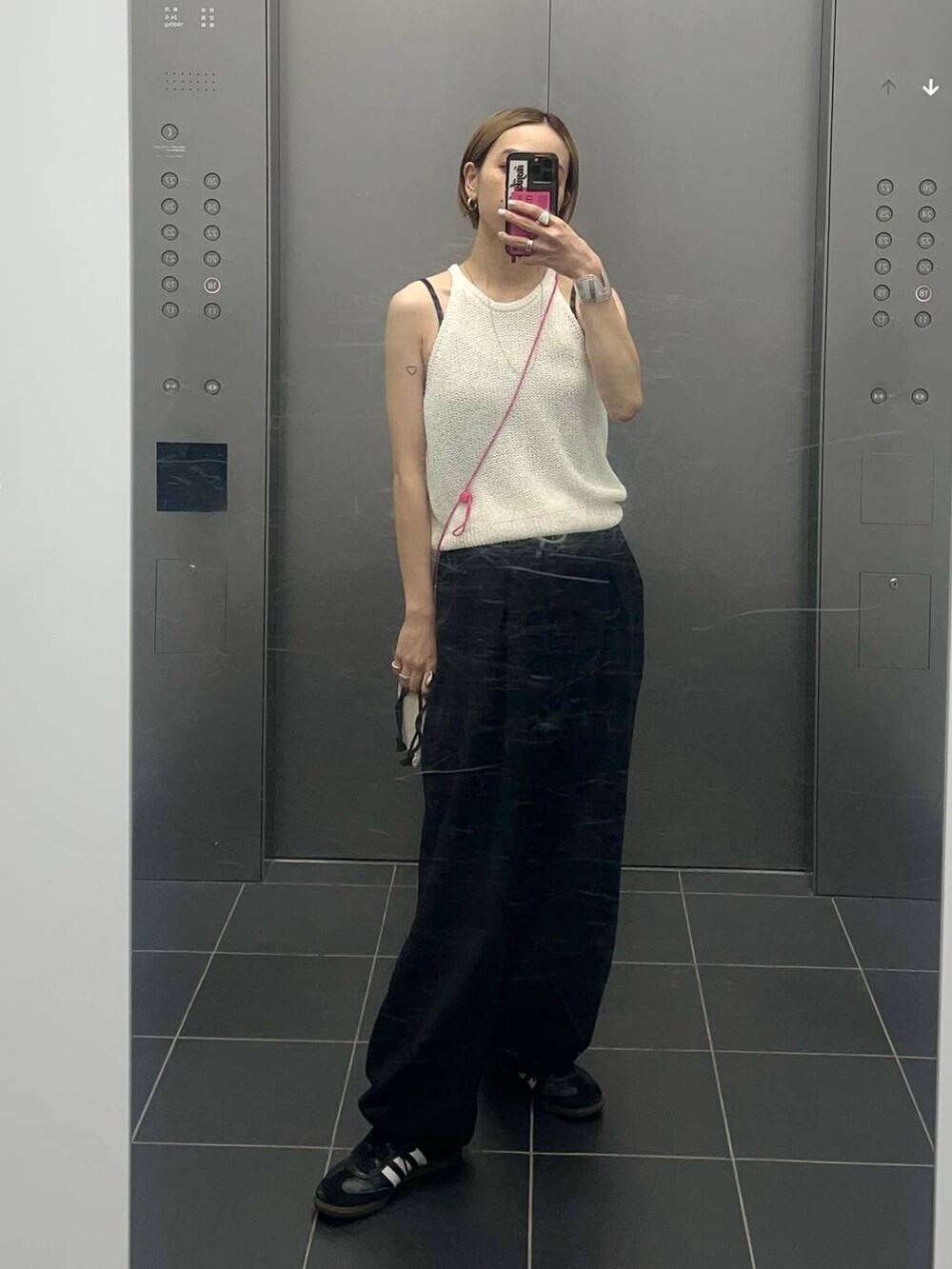 ホワイト系のキャミソール、ブラック系のスウェットパンツを着用したレディースの夏コーディネートの2枚目の写真