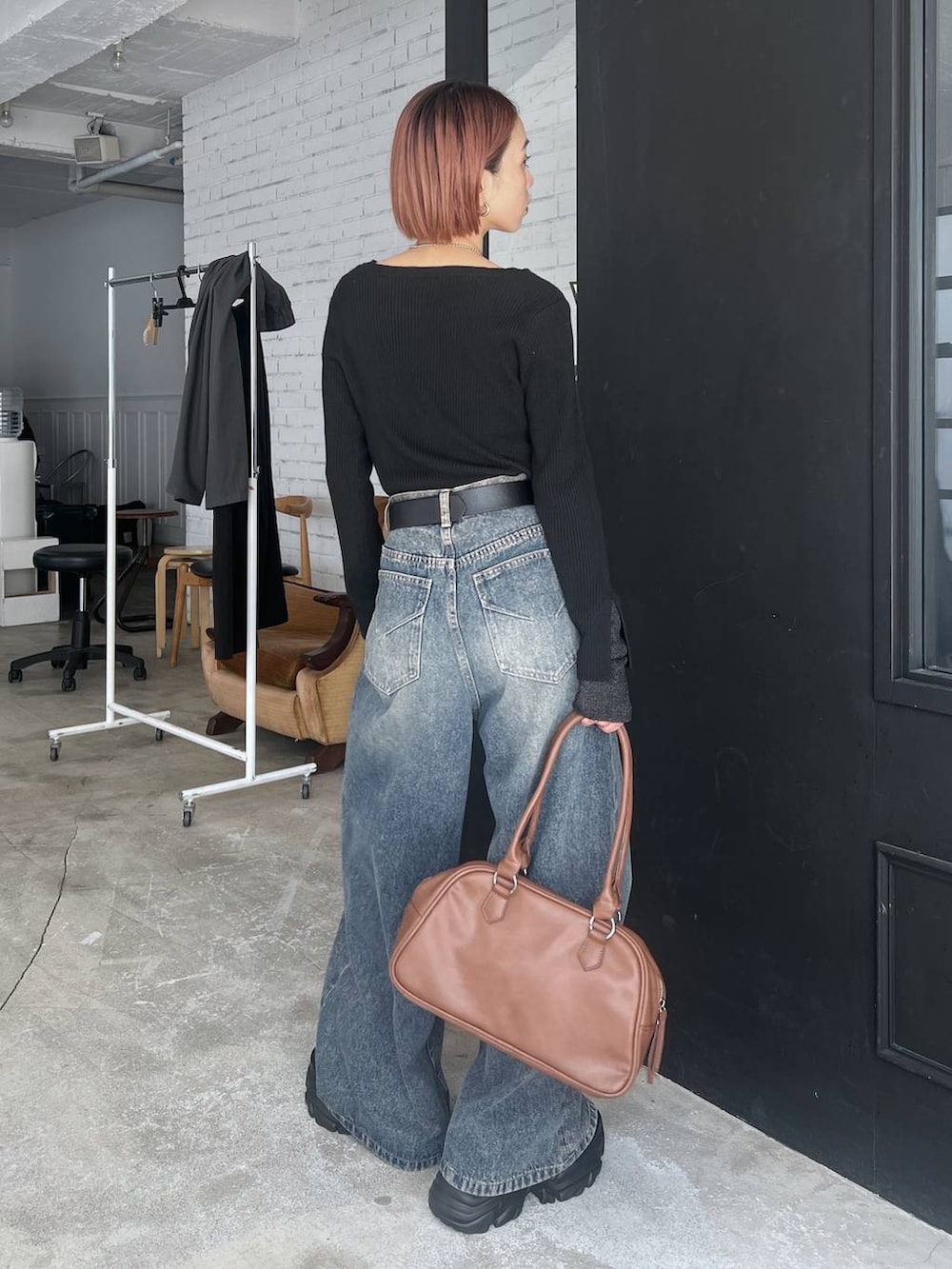 ブラック系のスニーカー、ブルー系のデニムパンツ、イエロー系のボストンバッグを着用したレディースの秋コーディネートの5枚目の写真