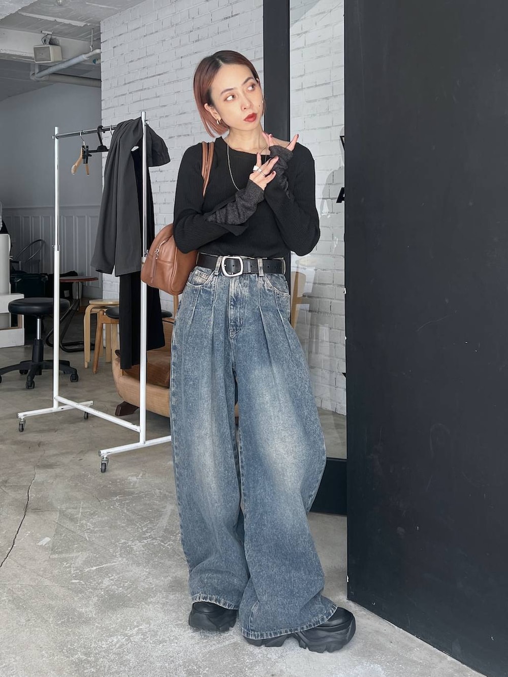 ブラック系のスニーカー、ブルー系のデニムパンツ、イエロー系のボストンバッグを着用したレディースの秋コーディネートの2枚目の写真