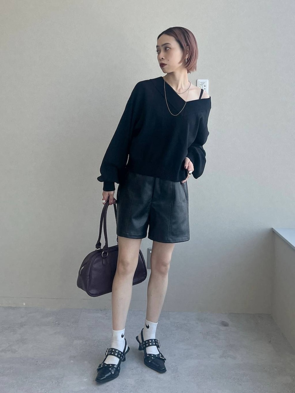 ブラック系のパンプス、レッド系のボストンバッグ、ブラック系のニット/セーターを着用したレディースの秋コーディネートの4枚目の写真