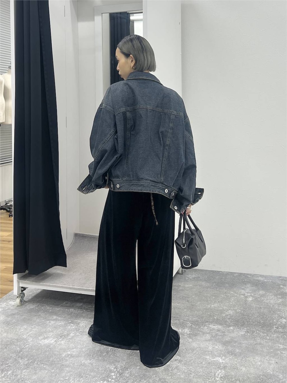 ブラック系のブーツ、ブルー系のデニムジャケット、ブラック系のショルダーバッグを着用したレディースの秋コーディネートの3枚目の写真