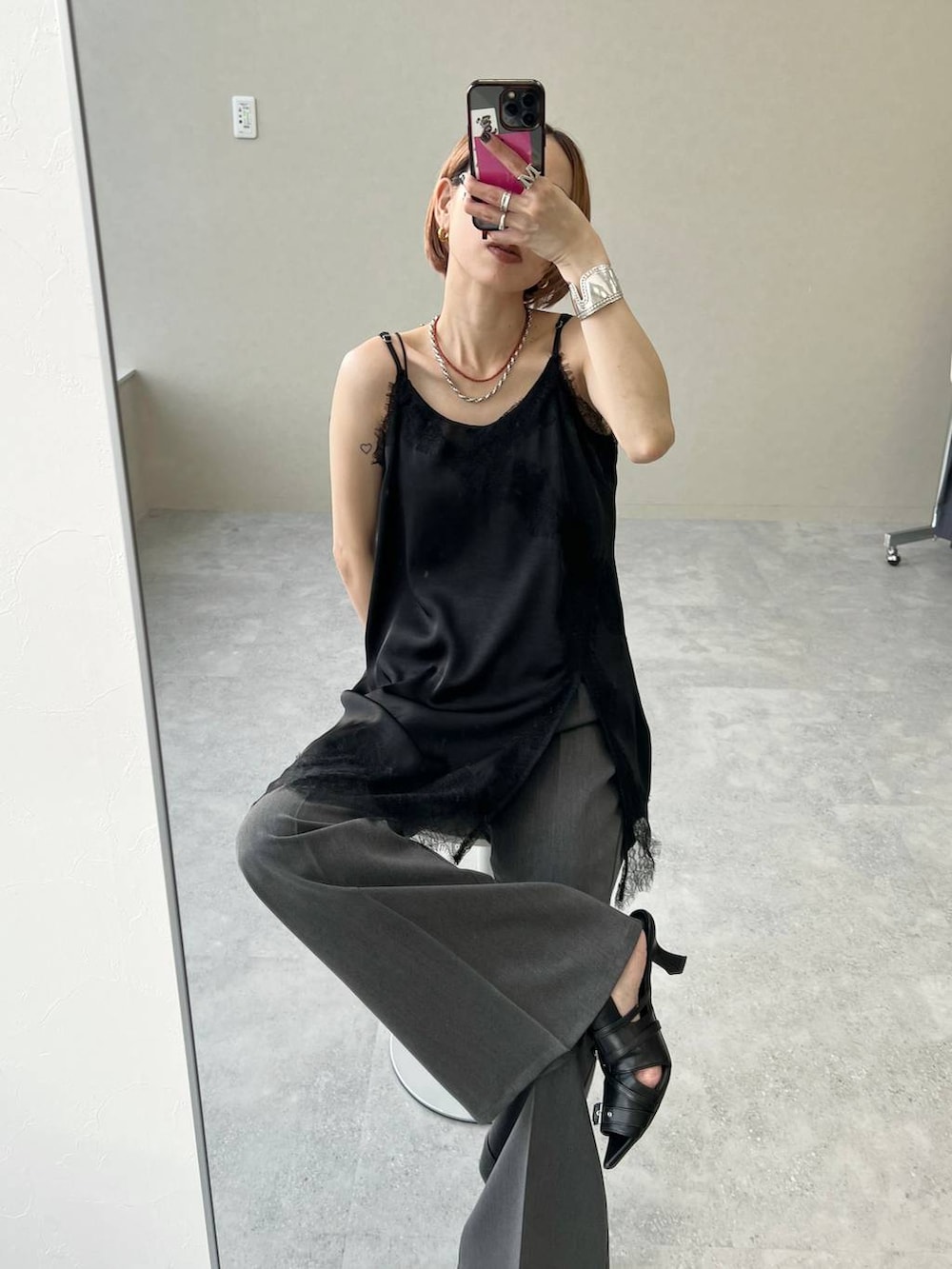 ブラック系のショルダーバッグ、ブラック系のチュニック、グレー系のスラックスを着用したレディースの夏コーディネートの2枚目の写真