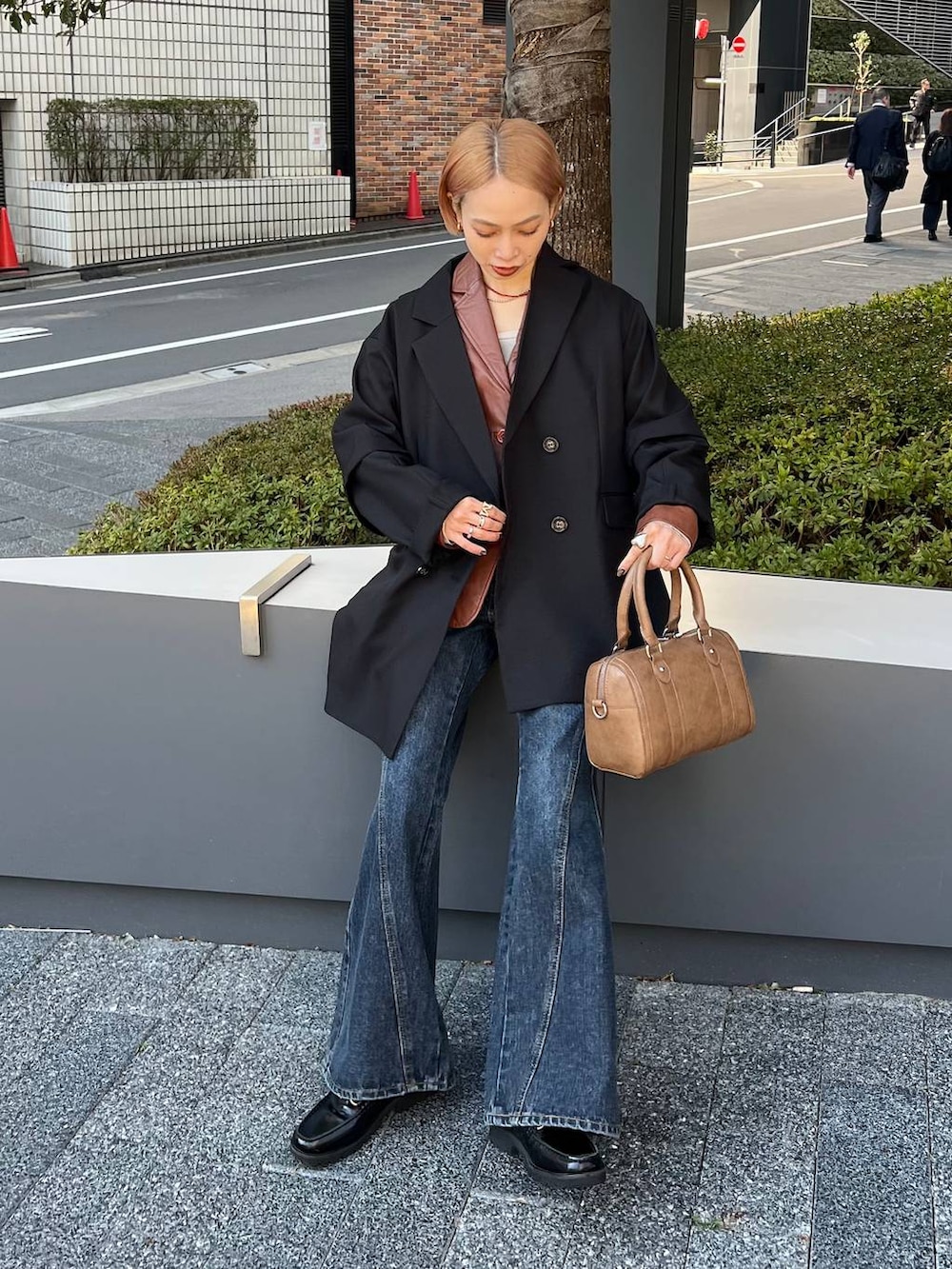 ブルー系のデニムパンツ、ブラウン系のボストンバッグ、ブラック系のテーラードジャケットを着用したレディースの春コーディネートの3枚目の写真