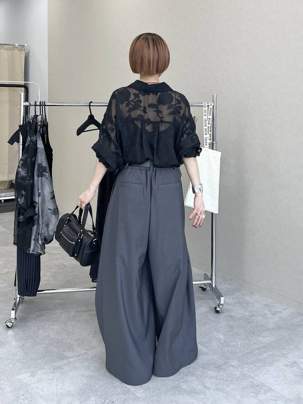ブラック系のショルダーバッグ、ブラック系のシャツ/ブラウス、グレー系のスラックスを着用したレディースの夏コーディネートの5枚目の写真