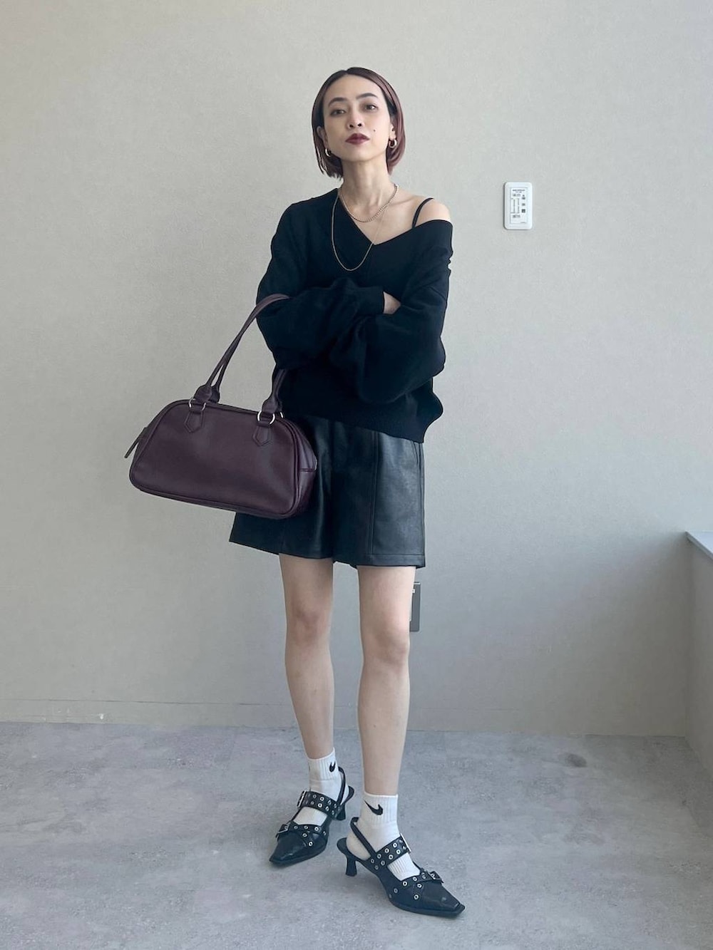 ブラック系のパンプス、レッド系のボストンバッグ、ブラック系のニット/セーターを着用したレディースの秋コーディネートの3枚目の写真