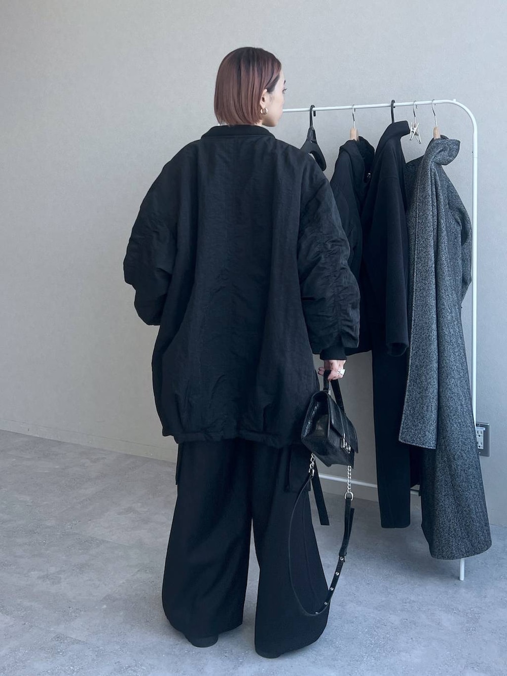 ブラック系のハンドバッグ、ブラック系のスラックス、ブラック系のブルゾンを着用したレディースの秋コーディネートの4枚目の写真