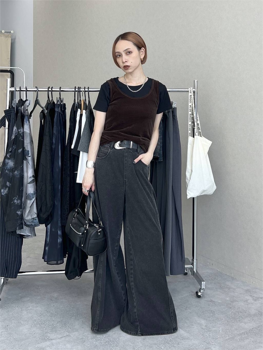 ブラック系のデニムパンツ、ブラック系のショルダーバッグ、ブラウン系のタンクトップを着用したレディースの夏コーディネートの2枚目の写真