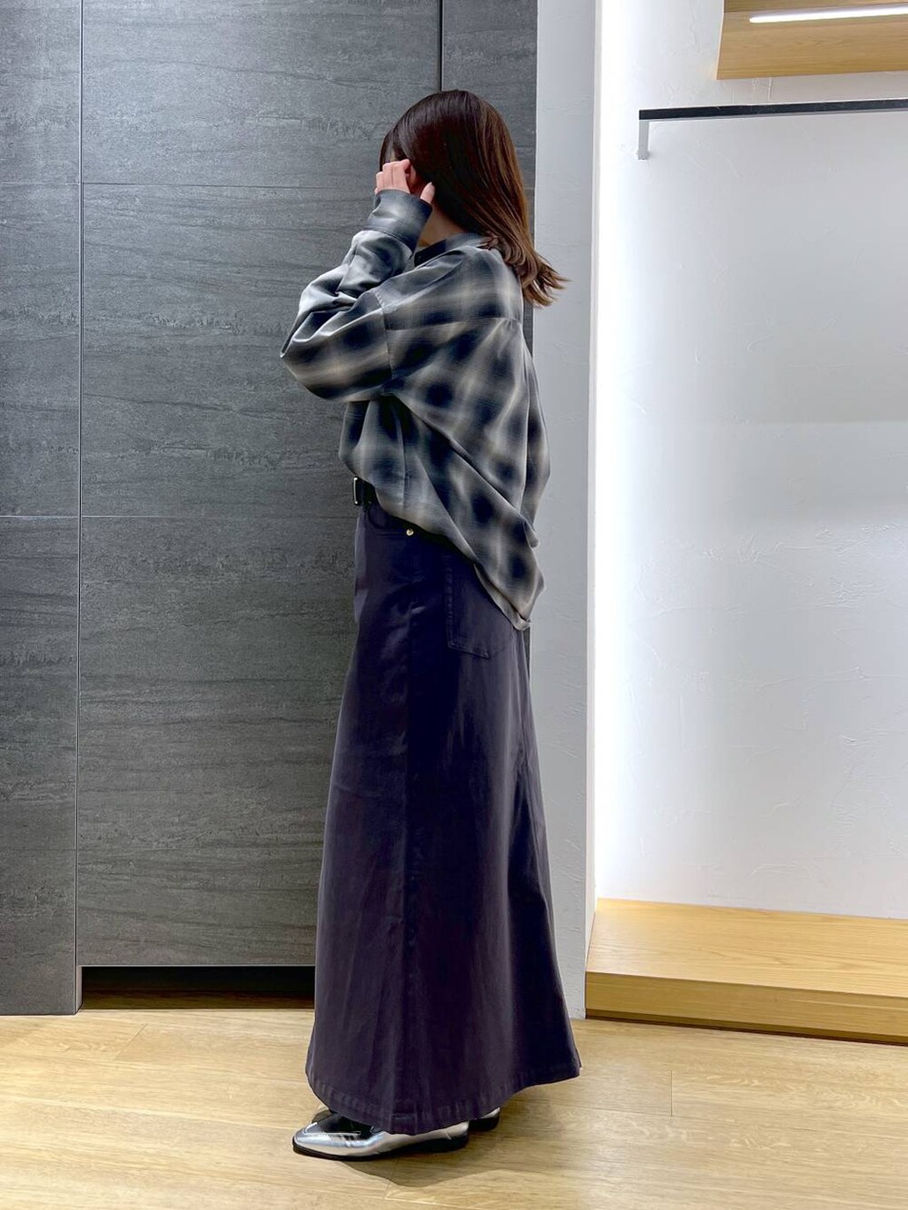 シルバー系のローファー、シルバー系のショルダーバッグ、グレー系のスカートを着用したレディースの冬コーディネートの2枚目の写真