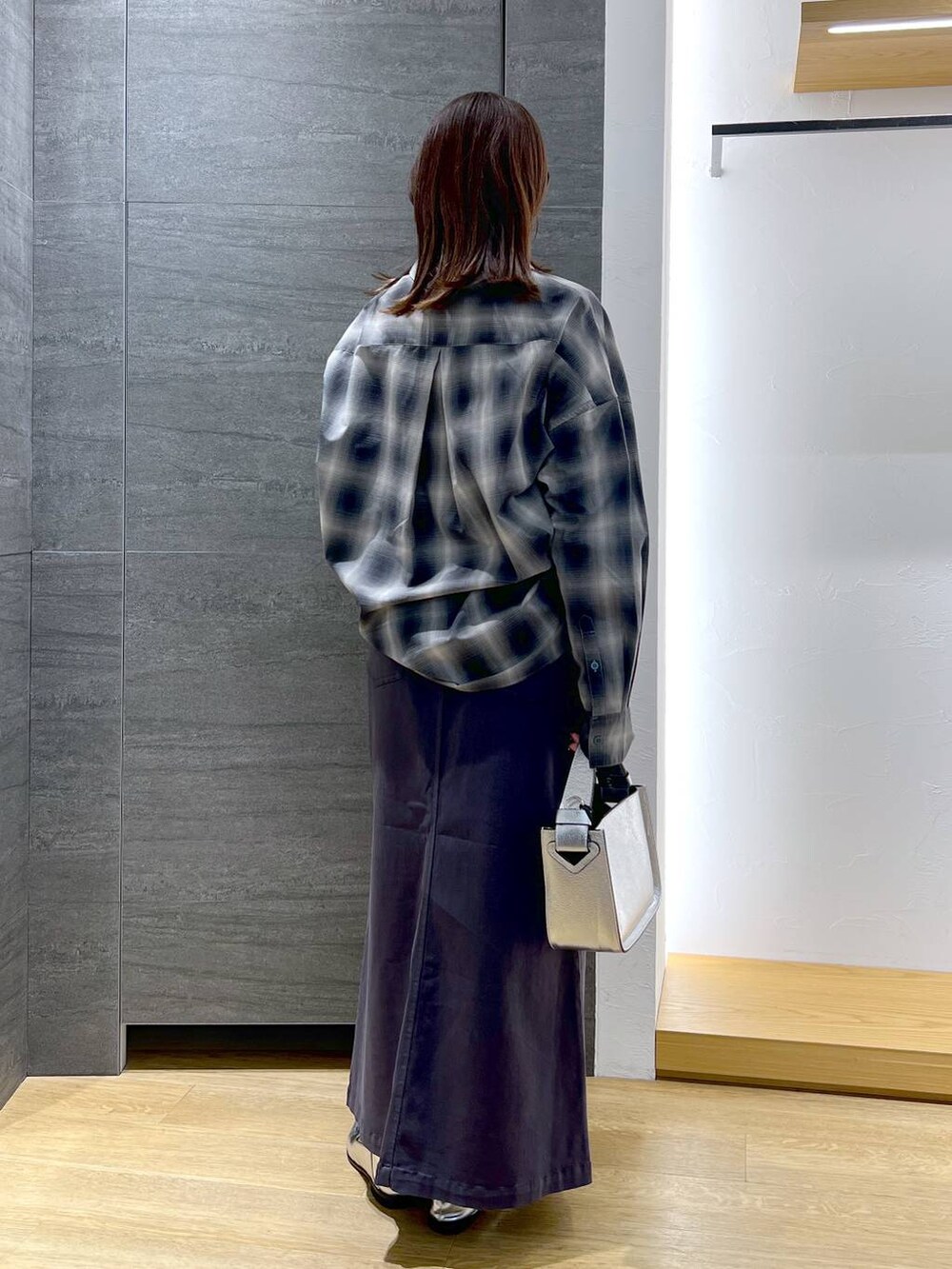 シルバー系のローファー、シルバー系のショルダーバッグ、グレー系のスカートを着用したレディースの冬コーディネートの3枚目の写真