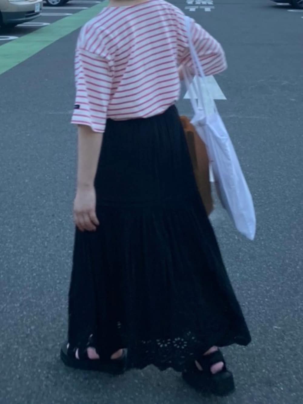 ブラック系のスカート、ピンク系のTシャツ/カットソー、ブラック系のサンダルを着用したレディースの春コーディネートの2枚目の写真