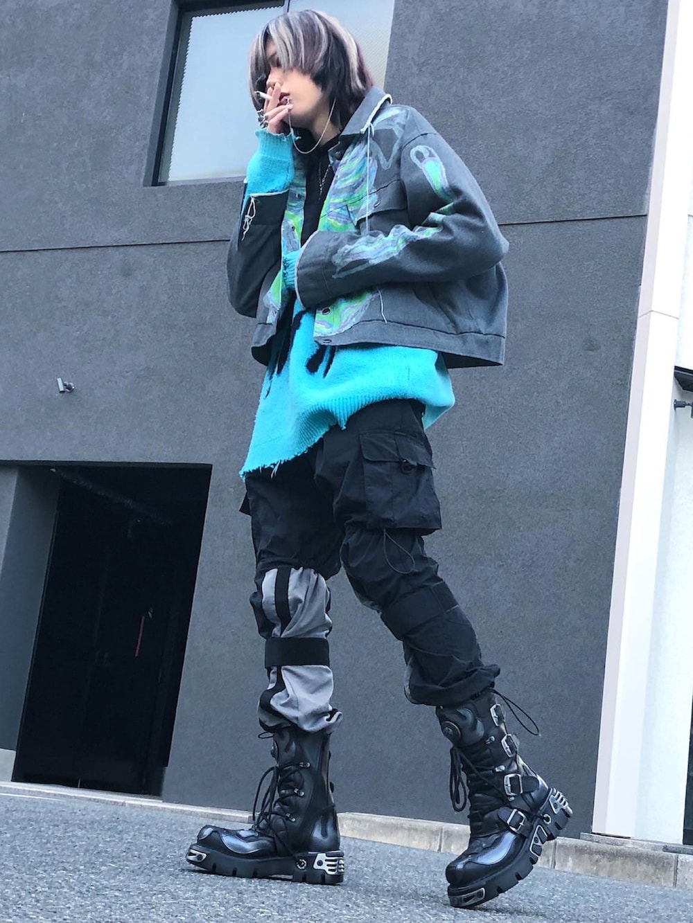 ブルー系のニット/セーター、ブラック系のカーゴパンツ、ブラック系のブーツを着用したメンズの春コーディネートの2枚目の写真