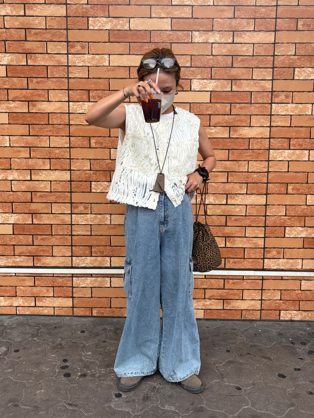 ブルー系のデニムパンツ、ホワイト系のベスト、その他のショルダーバッグを着用したレディースの夏コーディネートの2枚目の写真