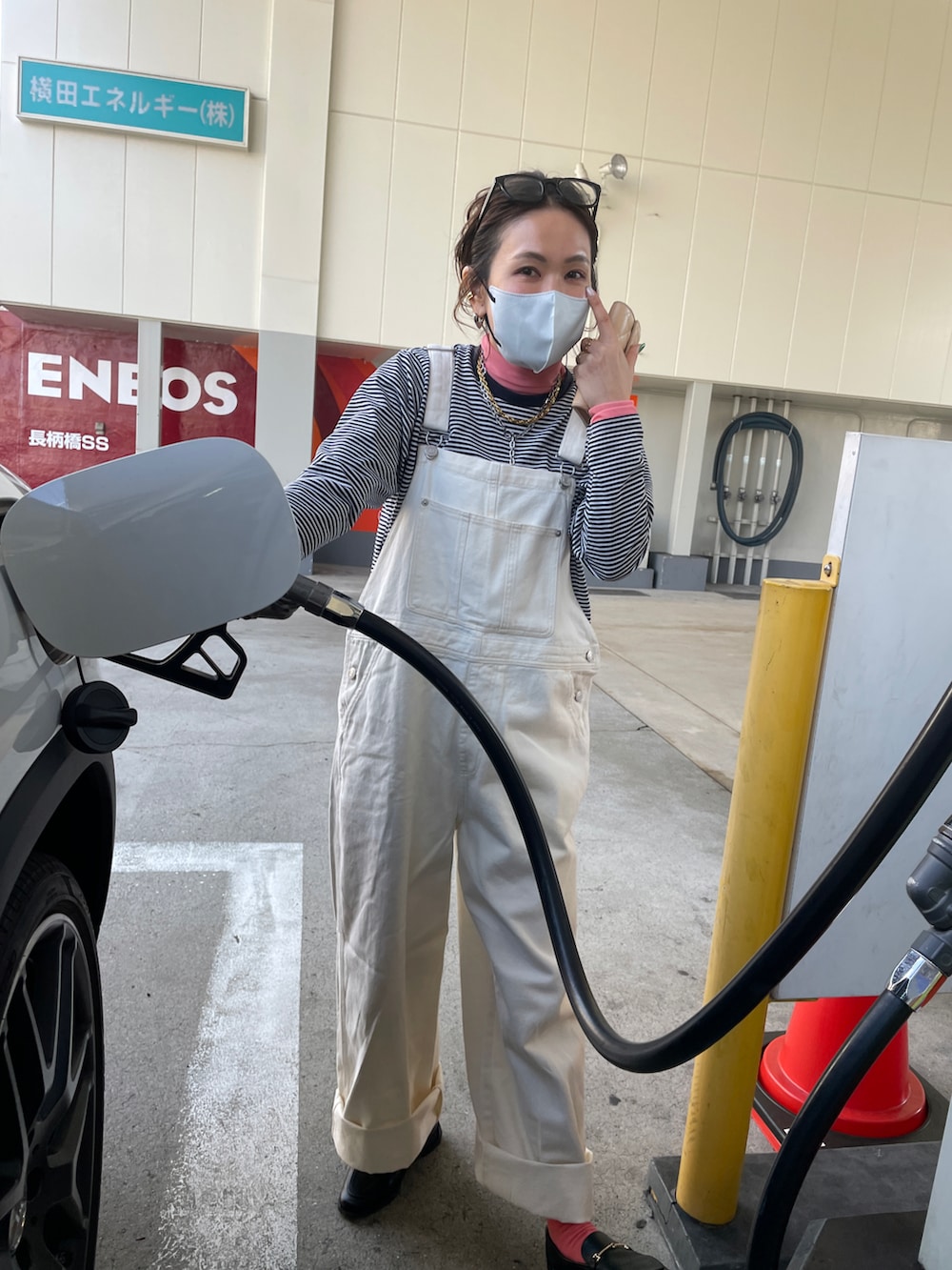 ブルー系のミリタリージャケット、ホワイト系のサロペット/オーバーオール、ホワイト系のハンドバッグを着用したレディースの春コーディネートの2枚目の写真