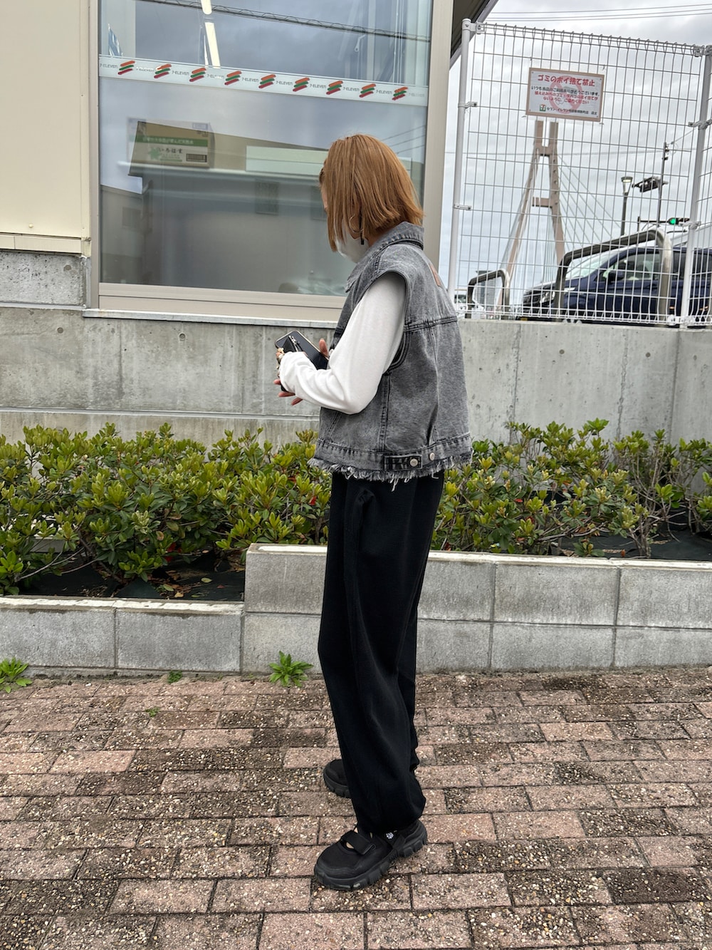 ホワイト系のTシャツ/カットソー、グレー系のベスト、ブラック系のサロペット/オーバーオールを着用したレディースの春コーディネートの2枚目の写真