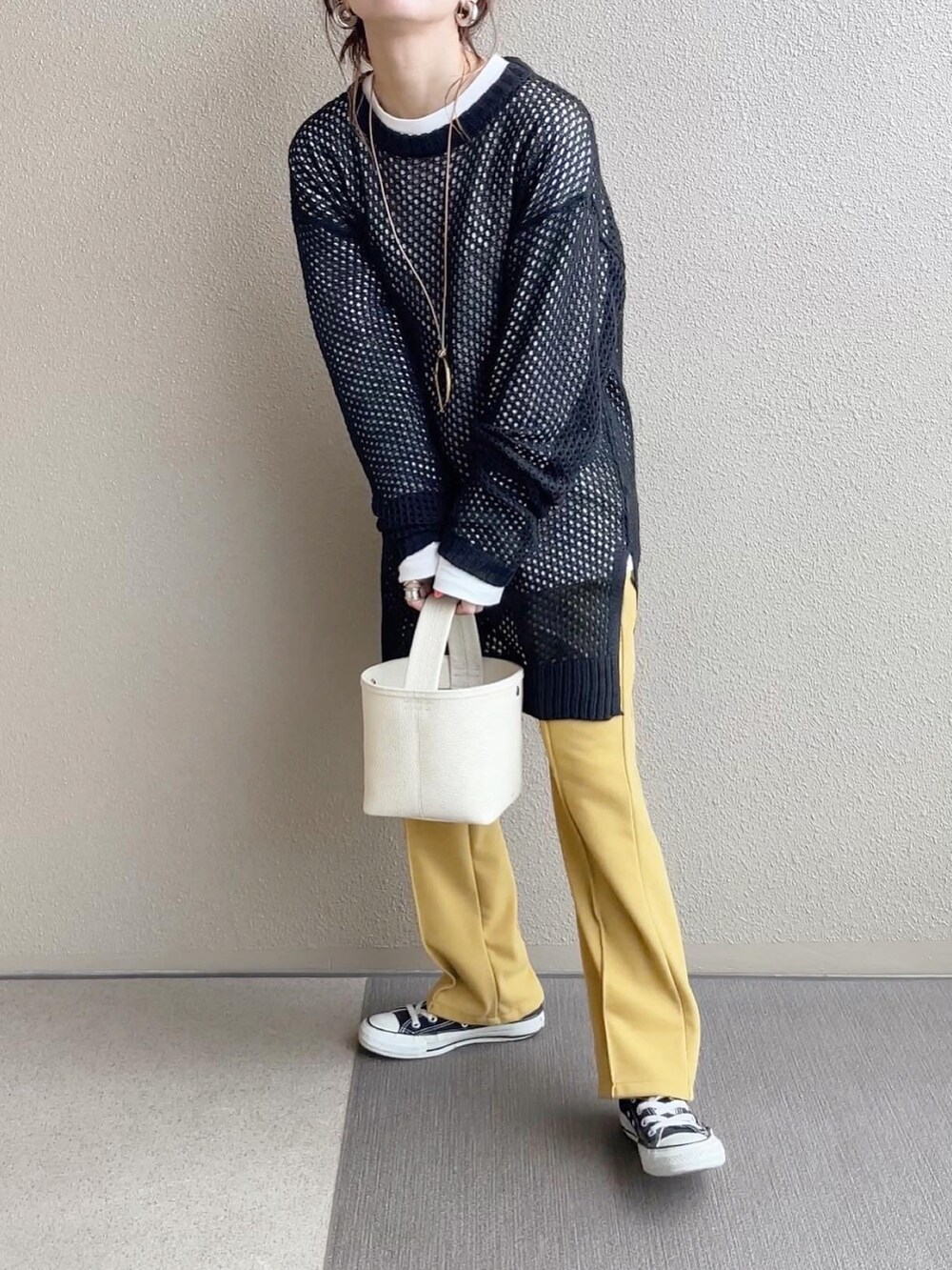 ブラック系のニット/セーター、イエロー系のその他パンツ、ホワイト系のTシャツ/カットソーを着用したレディースの冬コーディネートの2枚目の写真