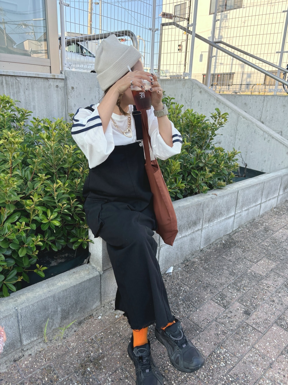 ブラック系のジャンパースカート、ブラック系のスニーカー、ベージュ系のニットキャップ/ビーニーを着用したレディースの秋コーディネートの4枚目の写真