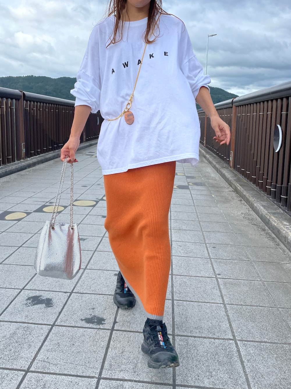 オレンジ系のスカート、ホワイト系のTシャツ/カットソー、シルバー系のショルダーバッグを着用したレディースの秋コーディネートの2枚目の写真