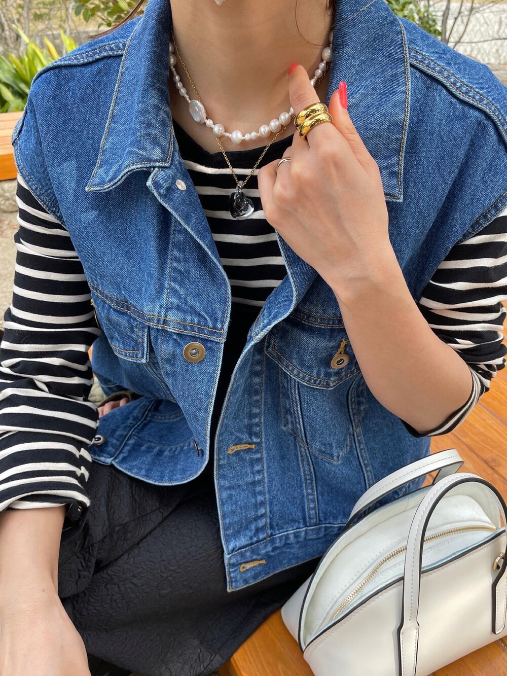 ブルー系のベスト、ブラック系のワンピース、ピンク系のスニーカーを着用したレディースの春コーディネートの5枚目の写真