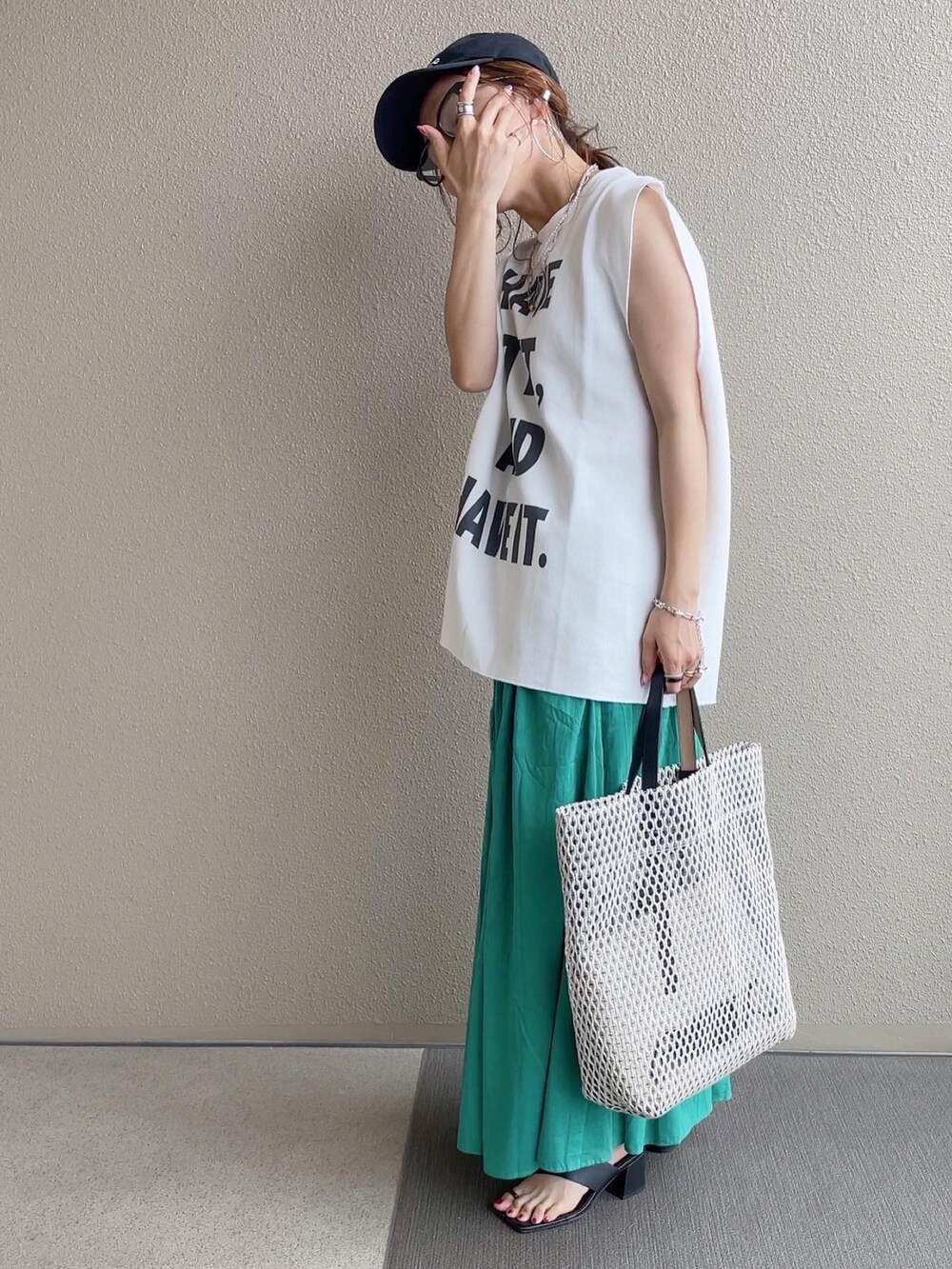 グリーン系のスカート、ホワイト系のトップス、ホワイト系のバッグを着用したレディースの春コーディネートの4枚目の写真