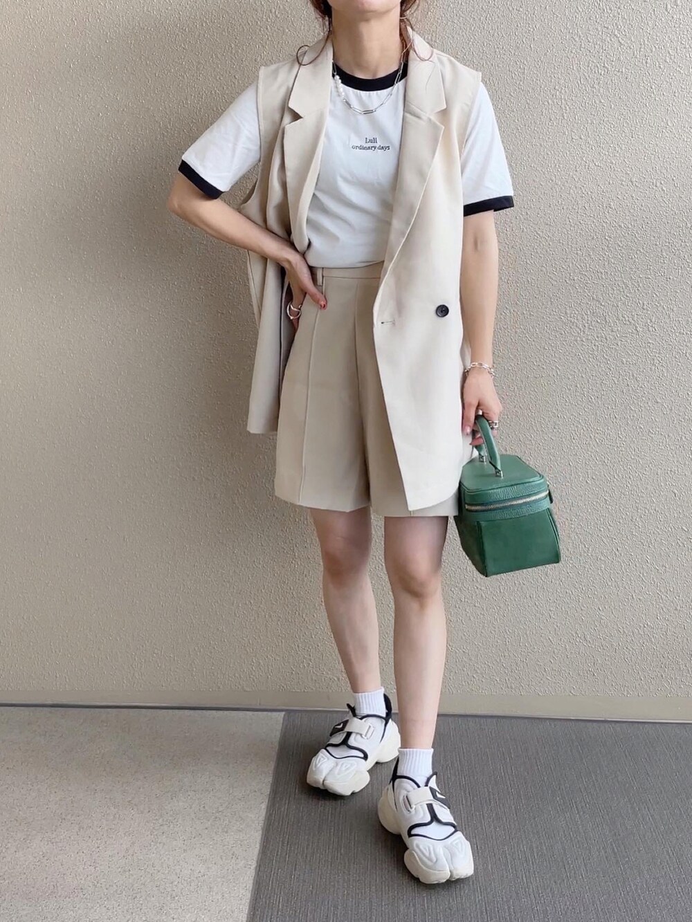 ホワイト系のスラックス、ブラック系のTシャツ/カットソー、ホワイト系のベストを着用したレディースの春コーディネートの3枚目の写真