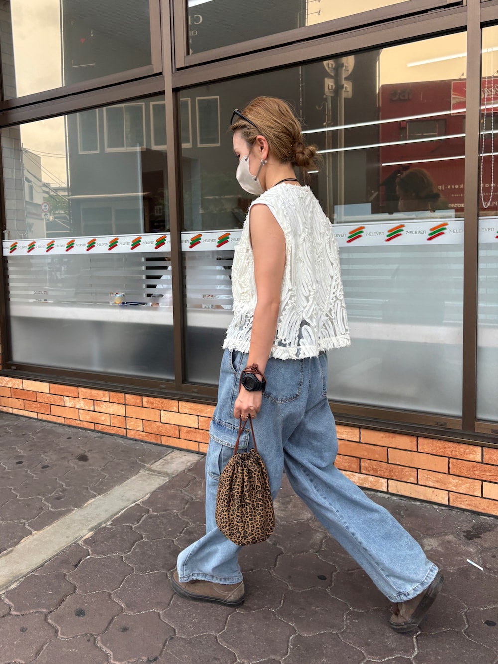 ブルー系のデニムパンツ、ホワイト系のベスト、その他のショルダーバッグを着用したレディースの夏コーディネートの3枚目の写真