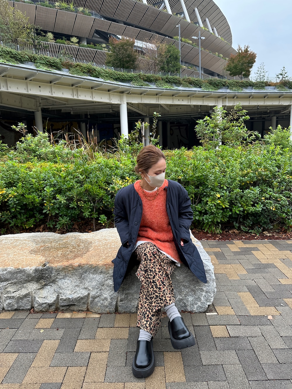 オレンジ系のニット/セーター、ブラウン系のその他パンツ、ブルー系のモッズコートを着用したレディースの冬コーディネートの3枚目の写真