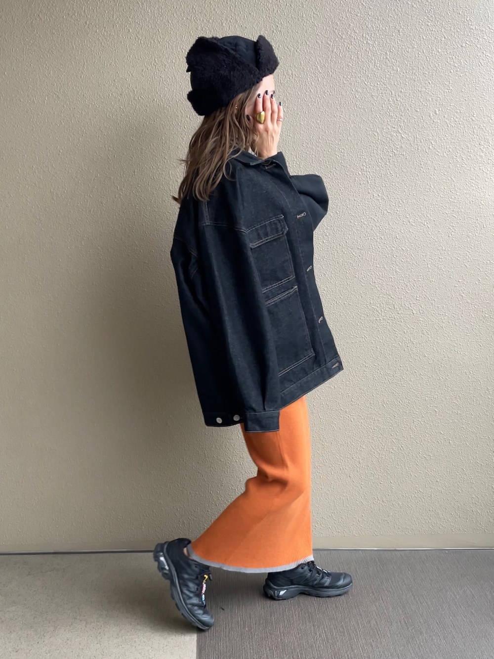 オレンジ系のスカート、ブラック系のスウェット、ブラック系のデニムジャケットを着用したレディースの秋コーディネートの2枚目の写真