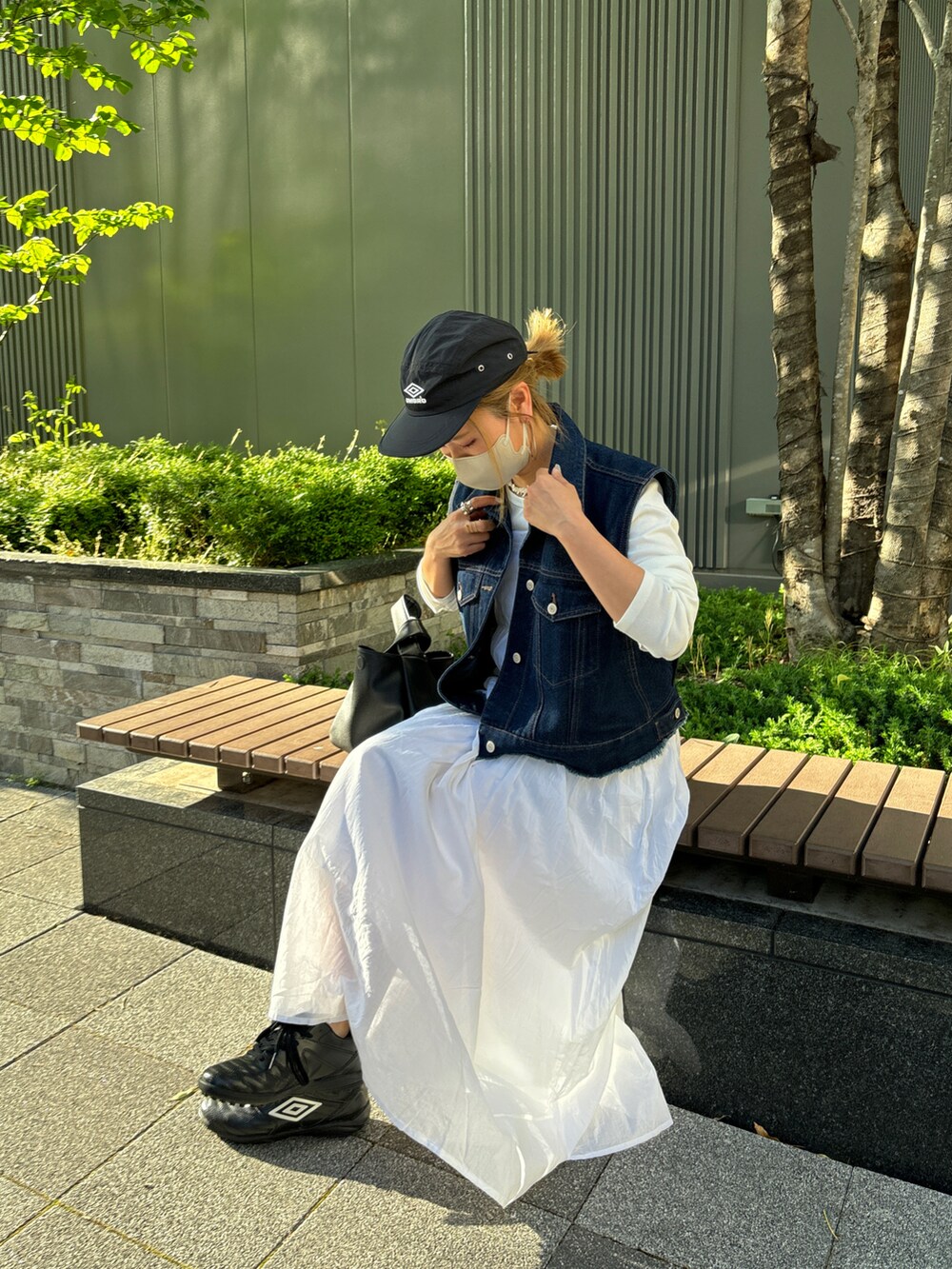 ブルー系のベスト、ホワイト系のワンピース、ブラック系のキャップを着用したレディースの春コーディネートの4枚目の写真