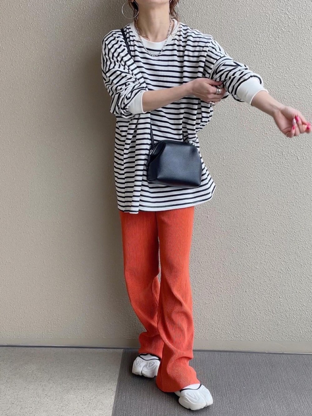 ブラック系のTシャツ/カットソー、ブラック系のスカート、オレンジ系のその他パンツを着用したレディースの春コーディネートの4枚目の写真