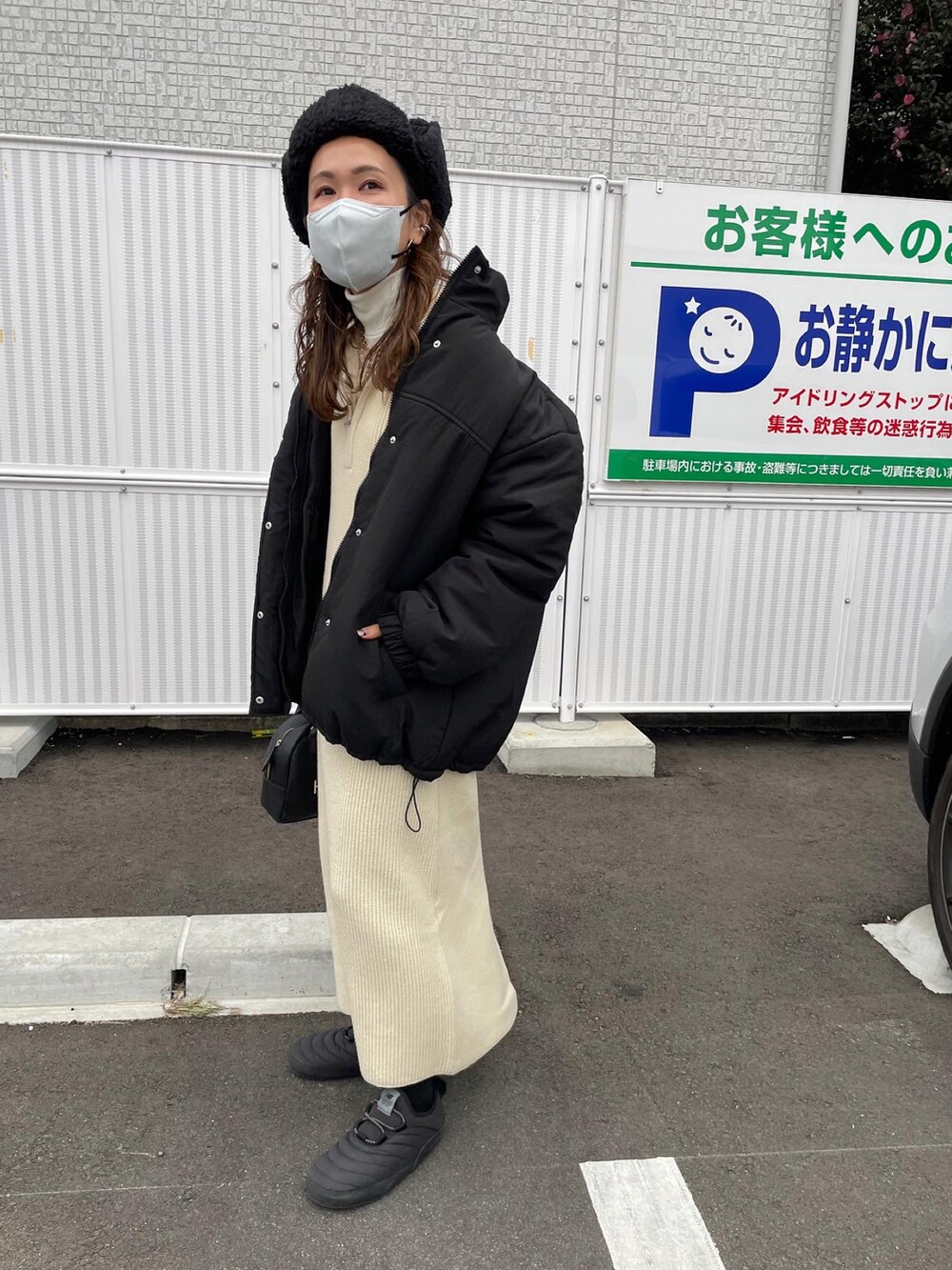 ホワイト系のワンピース、ブラック系のダウンジャケット/コート、ブラック系のハンドバッグを着用したレディースの冬コーディネートの3枚目の写真